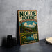 A vintage-style metal sign for the Nolde Forest Environmental Education Center in Pennsylvania, featuring a cabin surrounded by trees and a lake.