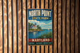 A vintage metal sign for North Point State Park in Maryland, featuring a lighthouse and a serene body of water.