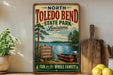 A vintage-style sign for North Toledo Bend State Park in Louisiana, featuring a scenic illustration of a lake, trees, and boats.