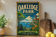 A vintage-style sign for Oakledge Park in Vermont, featuring a scenic lake and a building with a red roof.