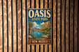 A vintage metal sign for Oasis State Park in New Mexico, featuring a scenic landscape with mountains, a lake, and palm trees.
