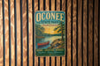A vintage metal sign for Oconee State Park in South Carolina, featuring a scenic illustration of a lake, trees, and a red canoe.