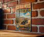 A vintage-style metal sign for the Ocotillo Wells State Vehicular Recreation Area, featuring a desert landscape with a blue off-road vehicle and the text "Adventure off the pavement - California".
