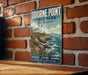 A vintage-style sign for Odionne Point State Park in New Hampshire, featuring a lighthouse and a coastal landscape.
