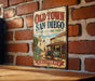 A vintage-style sign for Old Town San Diego, California, featuring a historical illustration of a town with a church, cactus, and wagon.