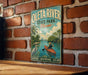 A vintage-style metal sign for Oleta River State Park in Florida, featuring a person kayaking and surrounded by palm trees and a city skyline.