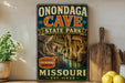 A vintage-style sign for Onondaga Cave State Park in Missouri, featuring an illustration of the cave and the text "Onondaga Cave State Park" prominently displayed.