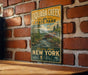 A vintage-style metal sign for Quagga Creek State Park, featuring a scenic illustration of a bridge and a river surrounded by trees.