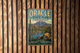 A vintage metal sign for Oracle State Park in Arizona, featuring a scenic mountain landscape with a cactus and a lake.