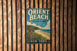 A vintage metal sign for Orient Beach State Park in New York, featuring a beach scene with a sign indicating the location.