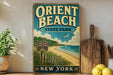 A vintage-style sign for Orient Beach State Park in New York, featuring a beach scene with a wooden fence and a sign indicating the location.