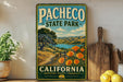 A vintage-style metal sign for Pacheco State Park in California, featuring a scenic landscape with a path, trees, and a lake.