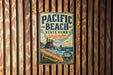 A vintage-style metal sign for Pacific Beach State Park in Washington, featuring a scenic coastal landscape with a rocky outcropping, beach, and ocean.