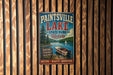 A vintage metal sign for Paintsville Lake State Park in Kentucky, featuring a scenic image of a boat on the lake and a forested landscape.