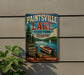A vintage-style metal sign advertising Paintsville Lake, a state park in Kentucky, featuring a scenic image of a lake, boats, and mountains.