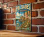 A vintage metal sign for Palisades State Park in South Dakota, featuring a scenic mountain landscape.