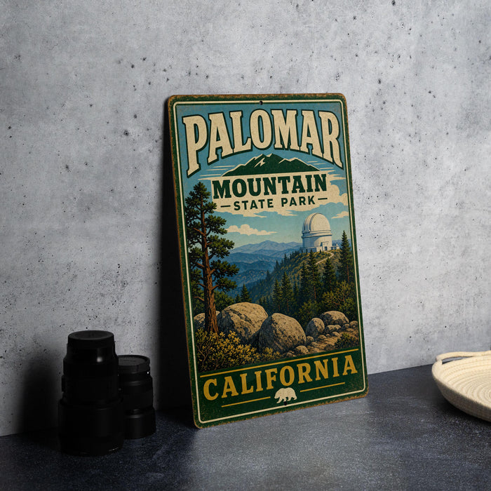 A vintage metal sign for Palomar Mountain State Park in California, featuring a scenic landscape with mountains, trees, and a dome-shaped building.