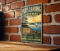 A vintage-style metal sign for Paris Landing State Park in Tennessee, featuring a scenic illustration of the park's lake and surrounding landscape.
