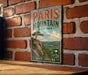 A vintage-style metal sign for Paris Mountain State Park in South Carolina is displayed on a brick wall.