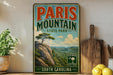 A vintage-style sign for Paris Mountain State Park in South Carolina, featuring a scenic landscape with a tree and mountains in the background.