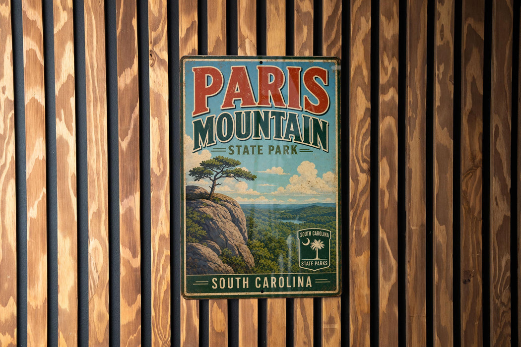 A vintage metal sign for Paris Mountain State Park in South Carolina, featuring a scenic landscape with a mountain, palm tree, and clouds.