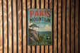 A vintage metal sign for Paris Mountain State Park in South Carolina, featuring a scenic landscape with a mountain, palm tree, and clouds.