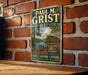 A vintage-style metal sign for Paul M. Grist State Park, featuring a scenic illustration of a lake, cabin, and mountains.