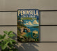 A vintage-style metal sign for Peninsula State Park in Wisconsin, featuring a scenic landscape with a lake, mountains, and a cave.
