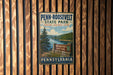A vintage Penn-Roosevelt State Park sign is displayed on a wooden wall, inviting visitors to explore and enjoy the park.