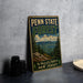 A vintage-style metal sign for Penn State Forest, featuring a scenic landscape with pine trees and mountains, is displayed on a gray concrete surface.