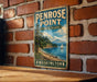 A vintage metal sign for Penrose Point State Park in Washington, featuring a scenic landscape with a mountain, trees, and a sailboat on the water.