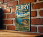 A vintage-style metal sign for Perry State Park in Kansas, featuring a scenic landscape with a lake and mountains.