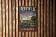 A vintage-style metal sign for Perryville Battlefield, a state historic site in Kentucky, mounted on a wooden fence.