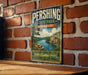 A vintage metal sign for Pershing State Park in Missouri, featuring a scenic landscape with a river, mountains, and a small boat.