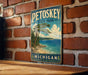 A vintage-style metal sign for Petoskey State Park in Michigan, featuring a scenic landscape with a pine tree, a lake, and mountains.