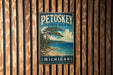 A vintage metal sign for Petoskey State Park in Michigan, featuring a scenic landscape with a pine tree, a lake, and mountains in the background.