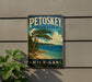 A vintage-style sign for Petoskey State Park in Michigan, featuring a scenic landscape with a pine tree, beach, and ocean.