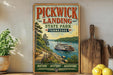 A vintage-style sign for Pickwick Landing State Park in Tennessee, featuring a scenic illustration of a riverboat on a wooden dock surrounded by lush greenery.