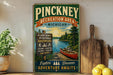 A vintage-style sign for the Pinckney Recreation Area in Michigan, featuring a scenic image of a lake, pine trees, and a canoe.