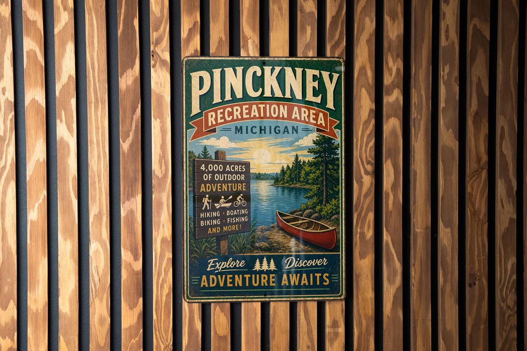 A vintage-style metal sign for the Pinckney Recreation Area in Michigan, featuring a scenic image of a lake and a canoe.
