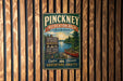 A vintage-style metal sign for the Pinckney Recreation Area in Michigan, featuring a scenic image of a lake and a canoe.