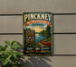 A vintage metal sign for the Pinckney Recreation Area in Michigan, featuring a scenic image of a lake, pine trees, and a canoe.