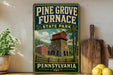 A vintage-style sign for Pine Grove Furnace State Park in Pennsylvania, featuring a red brick building and a stone tower surrounded by trees.