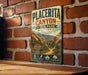 A vintage metal sign for Placerita Canyon State Park, California, featuring a scenic mountain landscape and text indicating the park's history and natural beauty.
