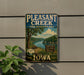 A vintage-style sign for Pleasant Creek State Recreation Area in Iowa, featuring a scenic landscape with a river, trees, and a picnic table.