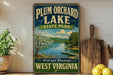 a vintage-style sign for Plum Orchard Lake State Park in West Virginia, with a scenic image of the lake and surrounding landscape.