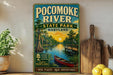 A vintage-style sign for the Pocomoke River State Park in Maryland, featuring a scenic illustration of a river, a dock, and a boat.