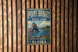 A vintage metal sign for Point Bridget State Park in Alaska, featuring a scenic landscape with mountains, a lake, and a rocky outcrop.