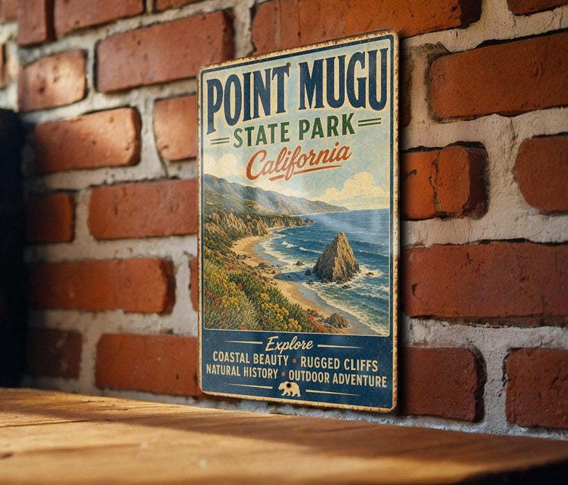 a vintage-style sign for Point Mugu State Park, California, mounted on a brick wall.