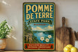 A vintage-style metal sign for Pomme Detrer State Park in Missouri, featuring a scenic landscape with a river, cliffs, and flowers.